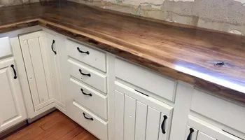 A kitchen with white cabinets and a wooden counter top.