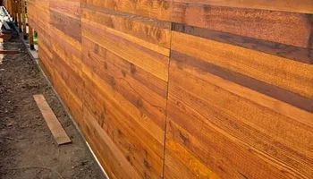 A wooden fence is being built on the side of a house.