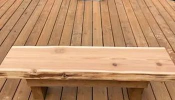 A wooden bench is sitting on top of a wooden deck.