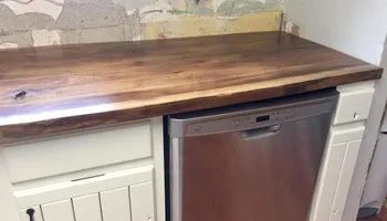 A kitchen with a wooden counter top and a stainless steel dishwasher.