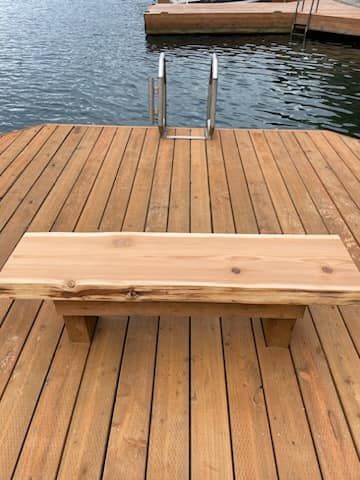 A wooden bench is sitting on top of a wooden dock next to a body of water.