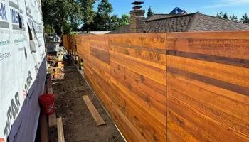 A wooden fence is being built in front of a house.