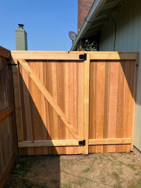 A wooden fence with a gate in the backyard of a house.