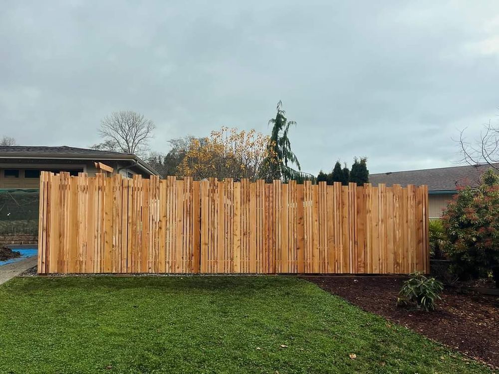 A wooden fence is sitting on top of a lush green lawn in front of a house.