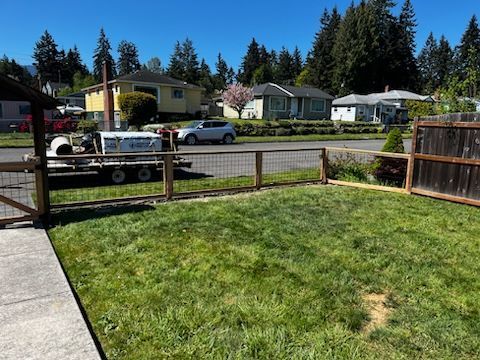 A backyard with a fence and a trailer parked in the grass.