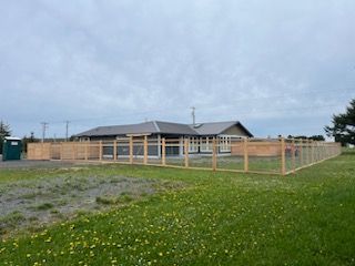 A wooden fence is surrounding a house in a grassy field.