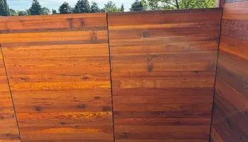 A close up of a wooden fence with trees in the background.