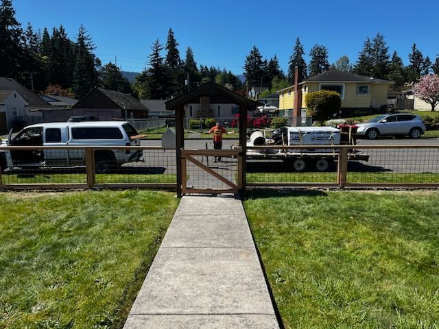 A white van is parked on the side of the road next to a wooden fence