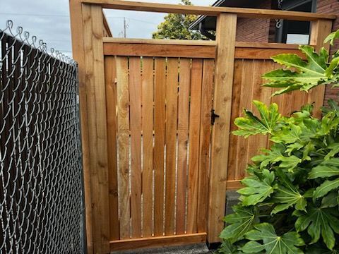 A wooden gate is sitting next to a chain link fence.