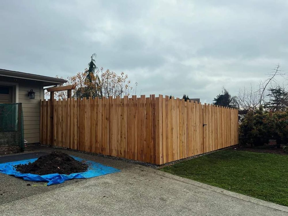 A wooden fence is being built in the backyard of a house.