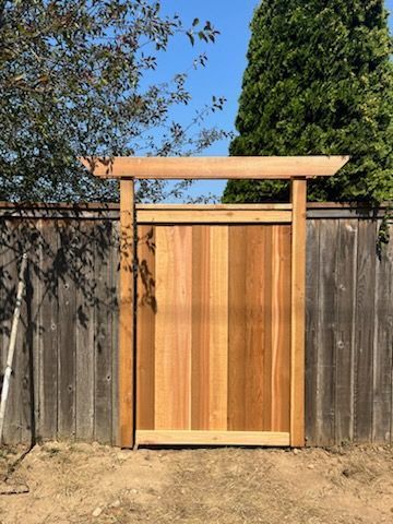 A wooden gate is sitting in front of a wooden fence.
