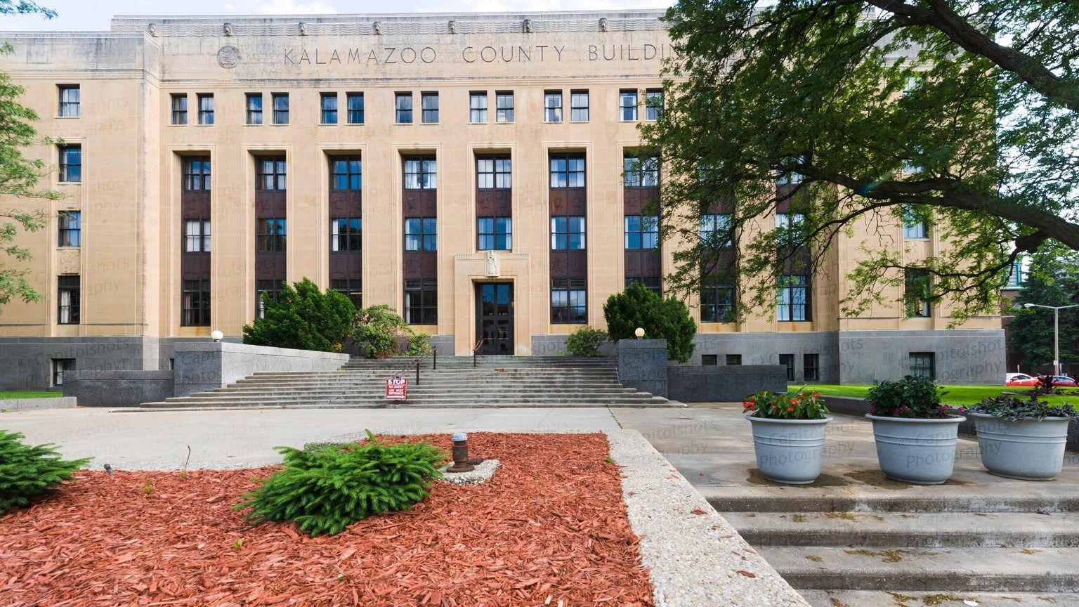 Tan brick county courthouse with steps leading to the entrance; landscaping in foreground.