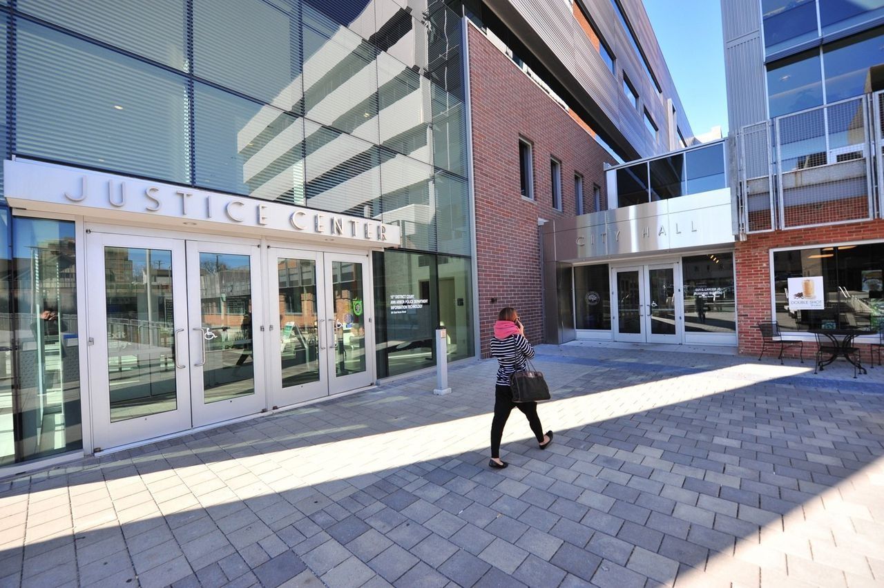 A person walks toward the Justice Center entrance, a modern building with glass and brick.