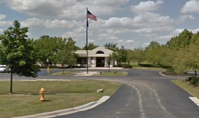 Building with American flag and winding driveway, on a partly cloudy day.