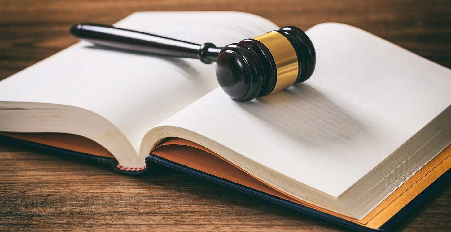 Open law book with a wooden gavel on top.