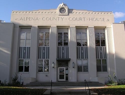 Alpena County Courthouse, a white Art Deco building with vertical lines and a clock.