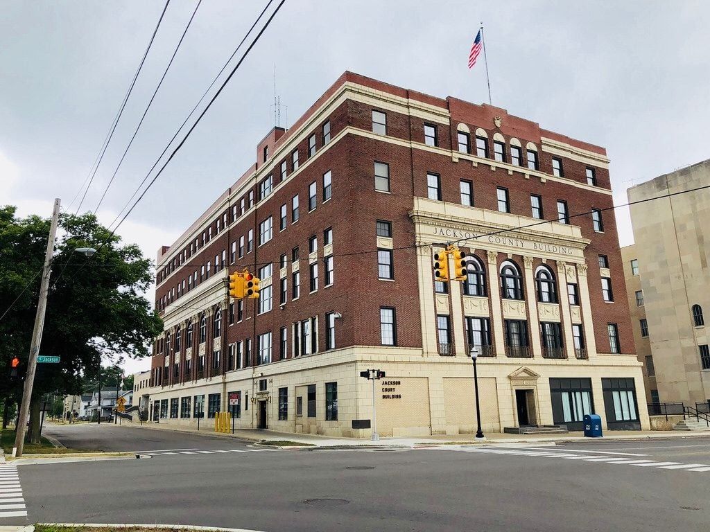 Brick building on a corner, with an American flag on top. Traffic lights and a tree are also visible.