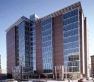Modern multi-story building with glass and brick facade, blue sky.