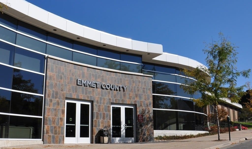 Emmet County building with curved glass facade, stone entrance, under a blue sky.