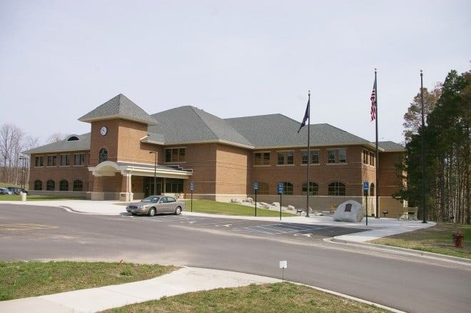 Brick building with clock tower and flags, car parked outside.