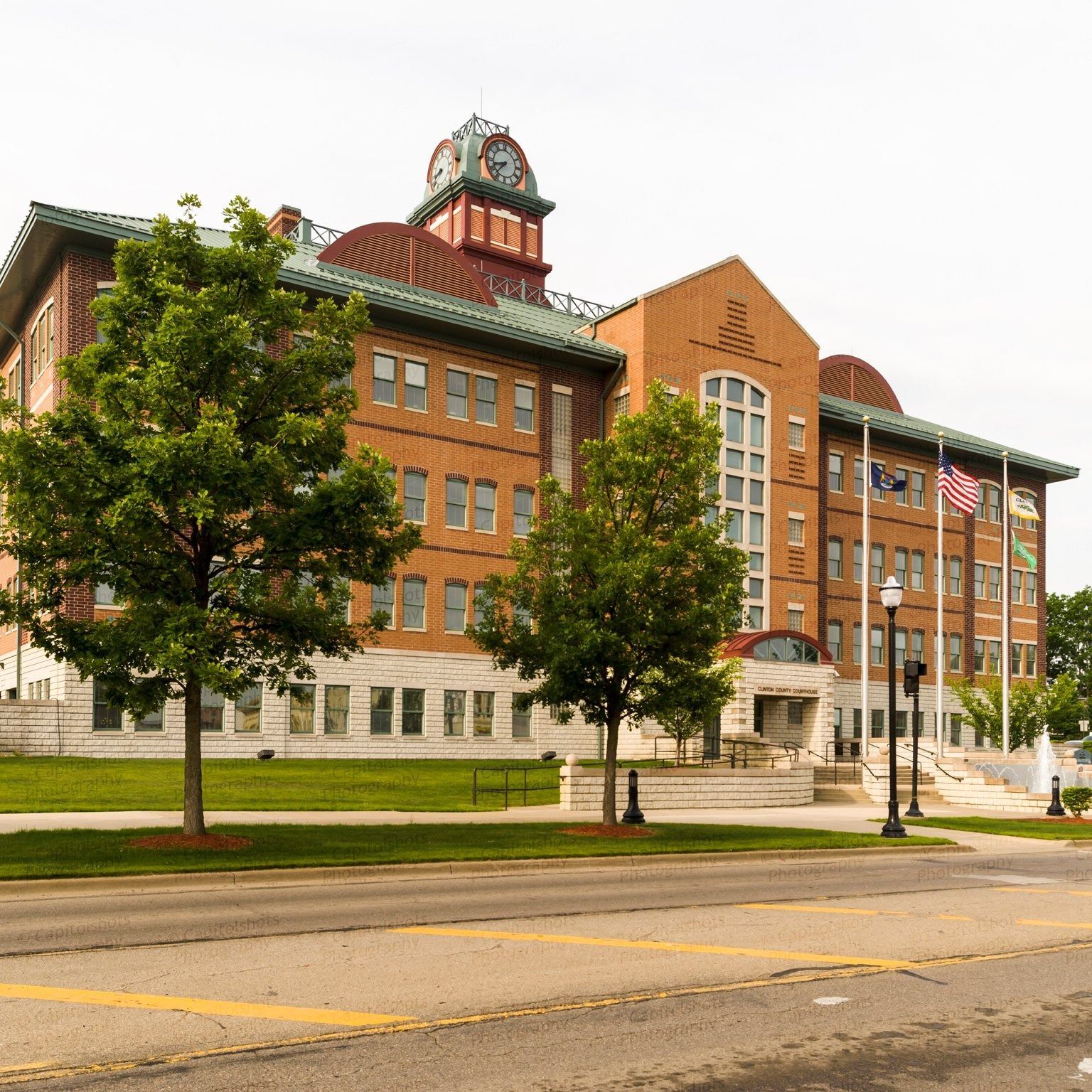 Brick courthouse building with a clock tower and flags on a sunny day.