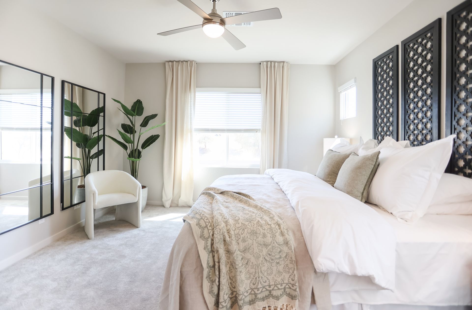 Bright white bedroom with bed, plants, mirrored closet, and large window with curtains