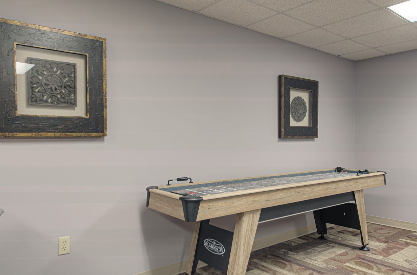 Pool table in a room with two framed artworks on the wall. The room has a neutral color scheme.