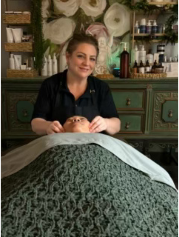 Woman receiving red light therapy treatment at a spa, lying down with eyes closed.