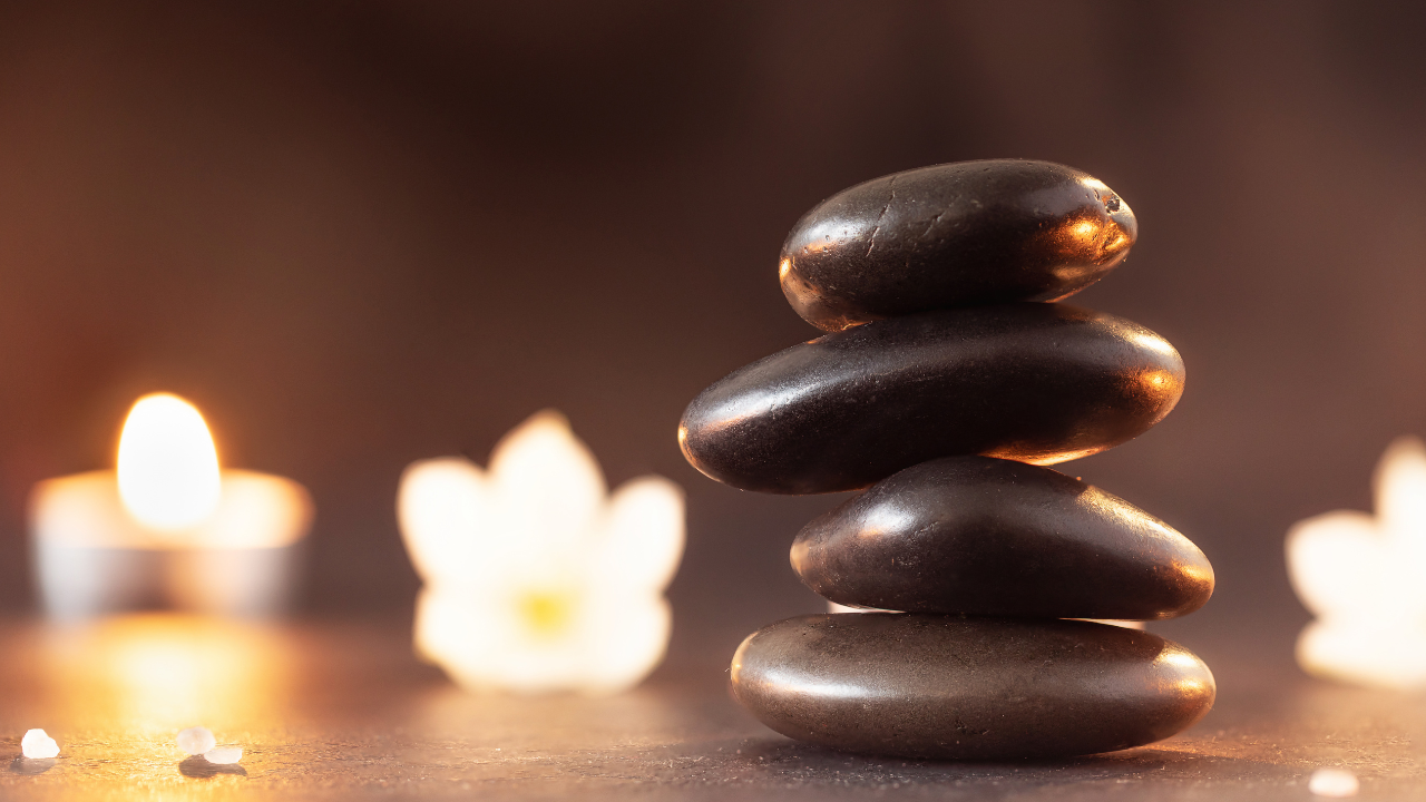 Stacked black stones with candles in a dimly lit, brown setting.