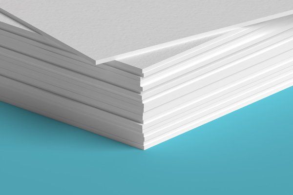 A close up of a stack of white sheets of paper on a blue surface.