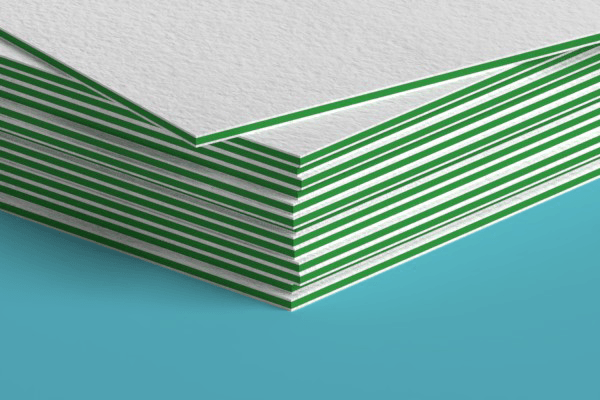 A close up of a stack of white and green business cards on a blue surface.