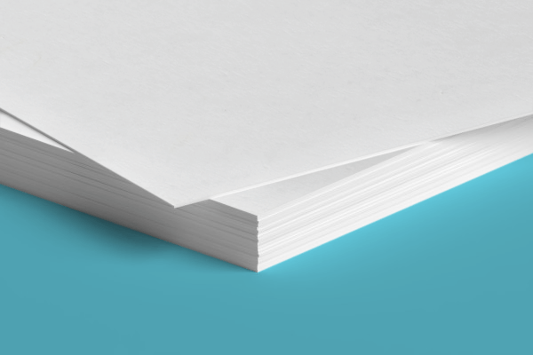 A close up of a stack of white paper on a blue surface.