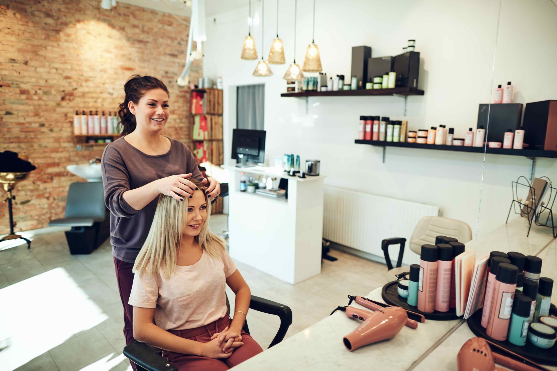 Hair stylist styling a client's hair in a salon. The stylist is standing behind the client, who is seated.