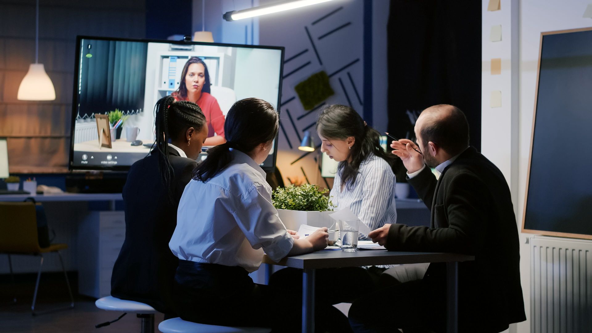 A group of people are sitting around a table having a video conference.