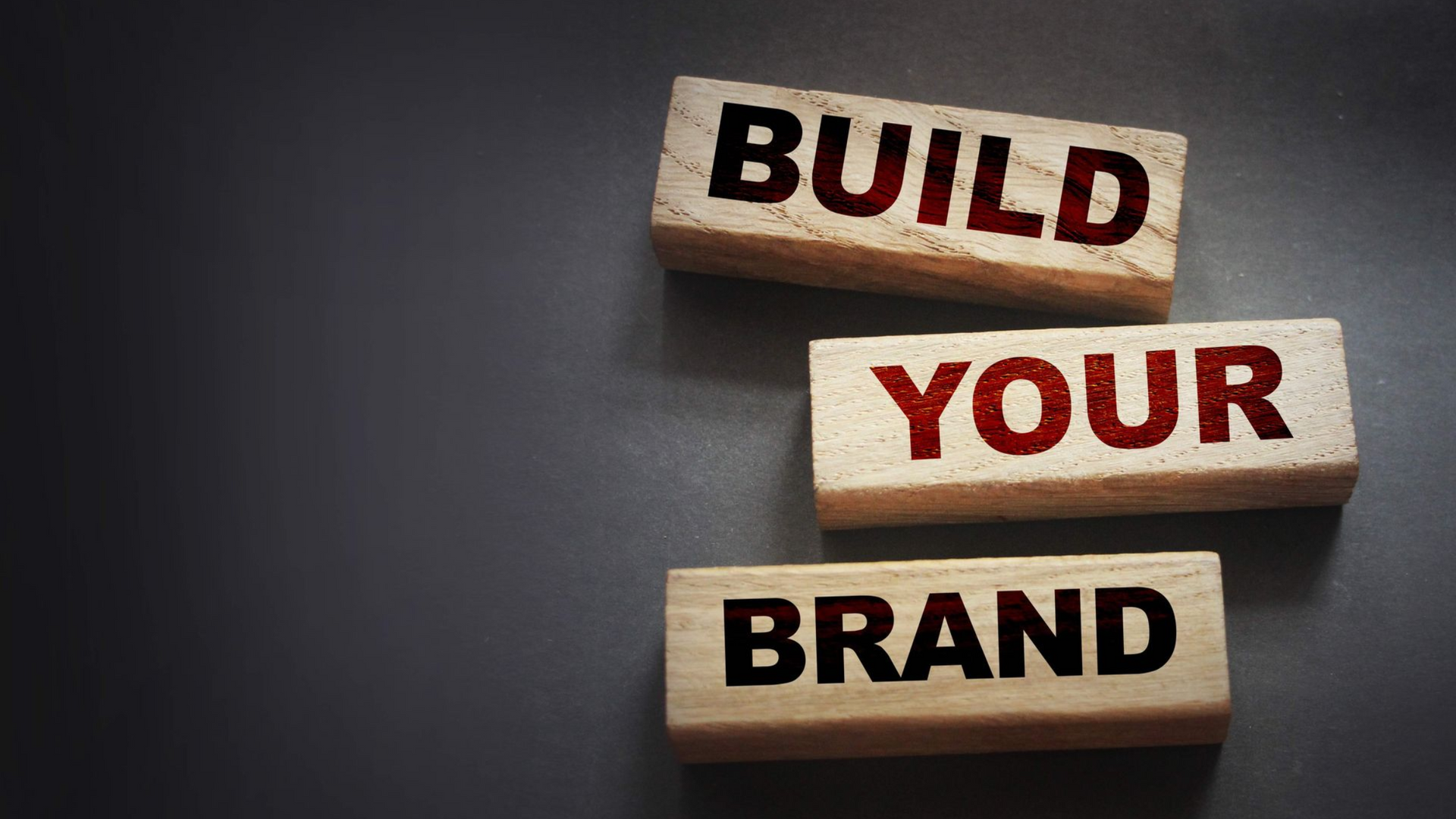 Three wooden blocks arranged on a dark background, each displaying one word: 