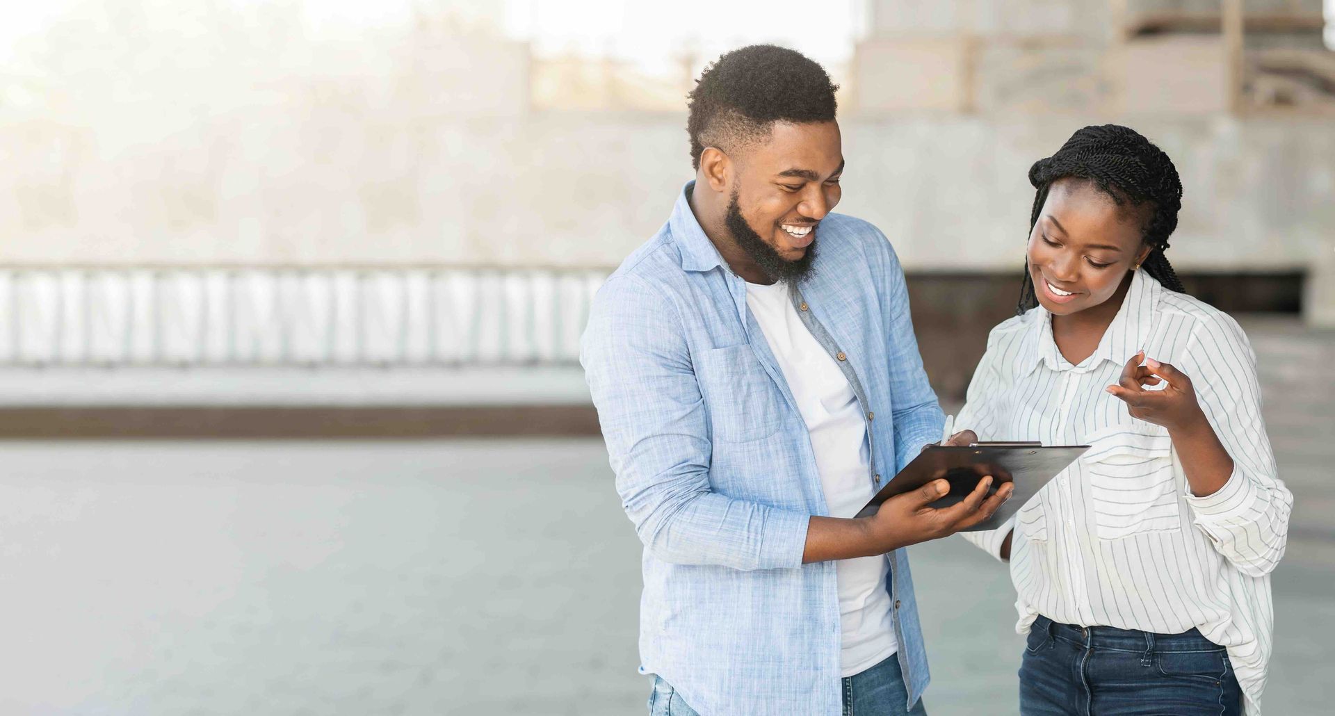 A black male and female are smiling and looking at a tablet.