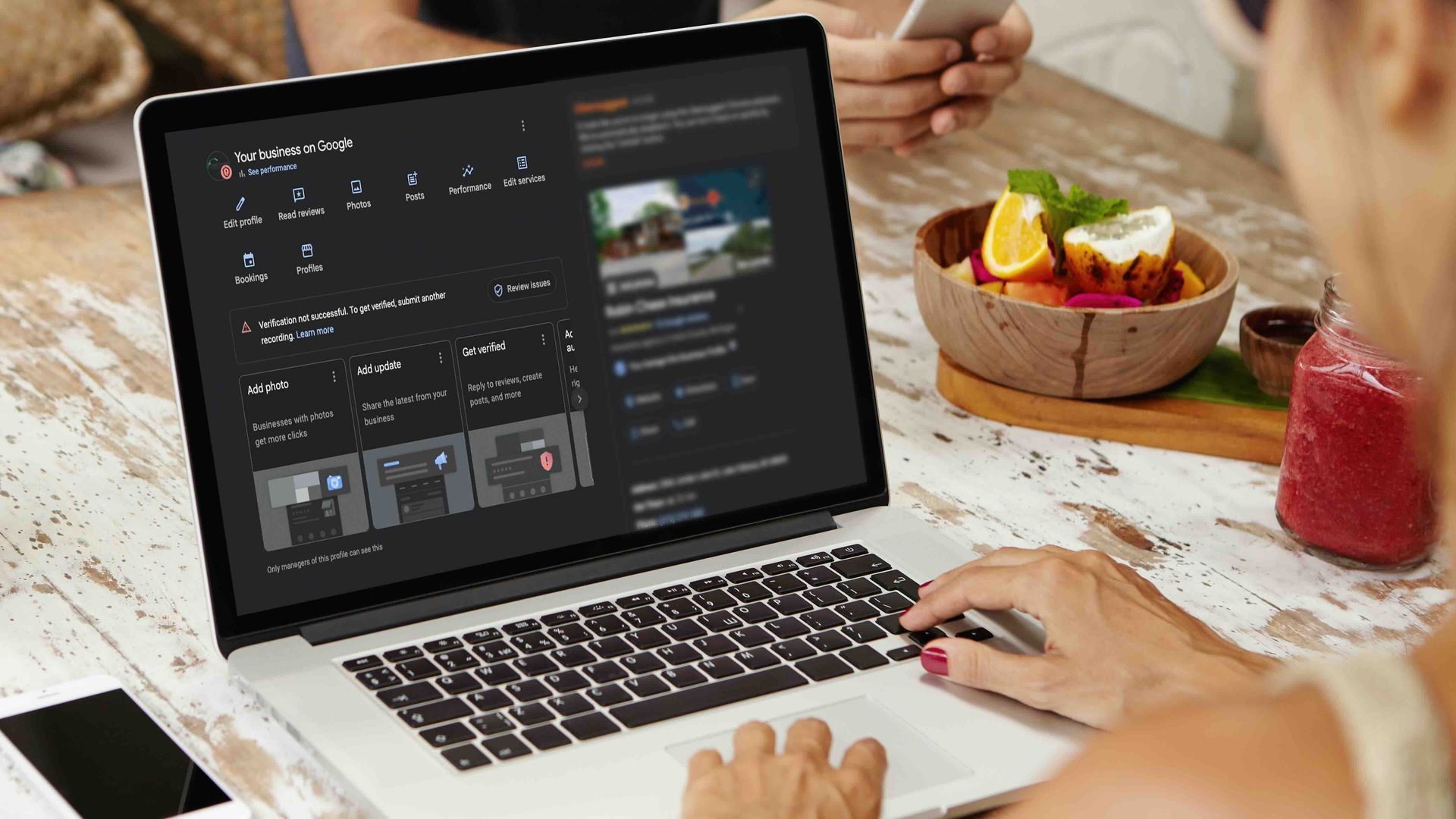 Woman using a laptop, fruit bowl, and juice on a wooden table.
