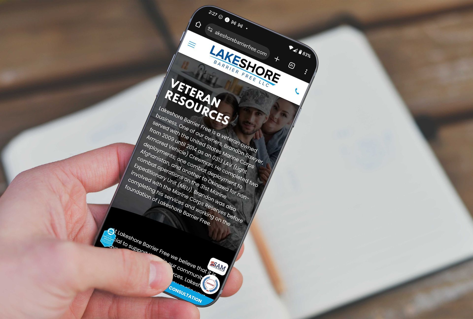 A person is holding a cell phone with the Lakeshore Barrier Free website on it.