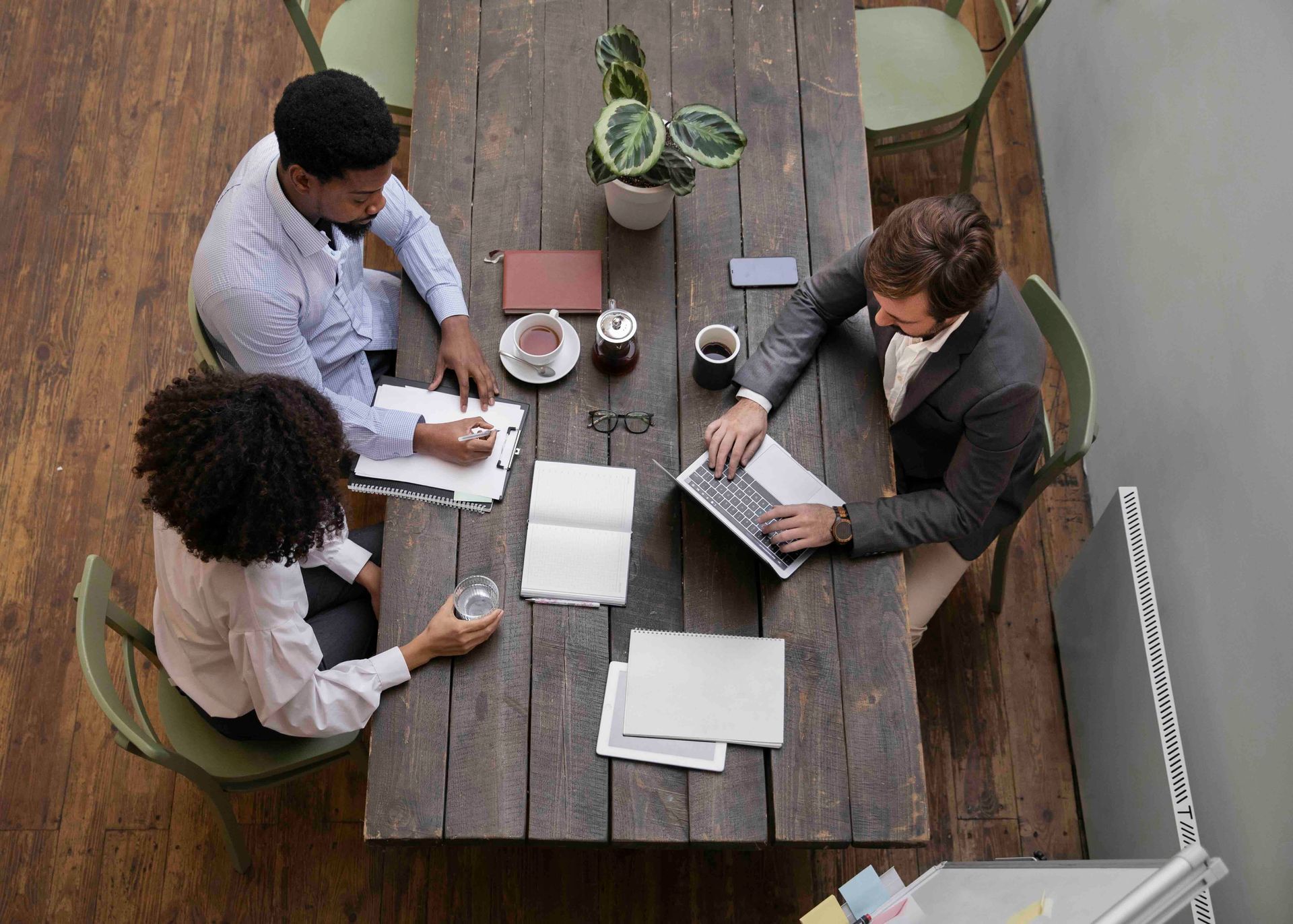 A group of people are sitting around a wooden table.