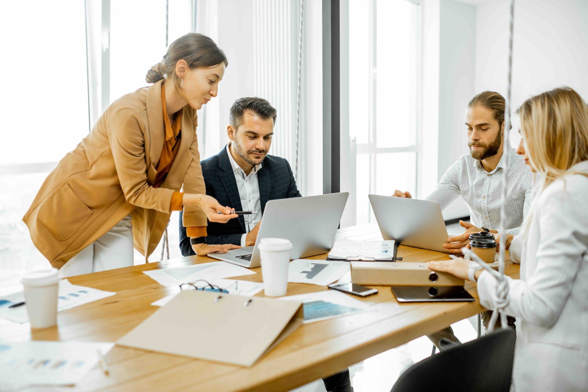 A group of people are sitting around a table with laptops.