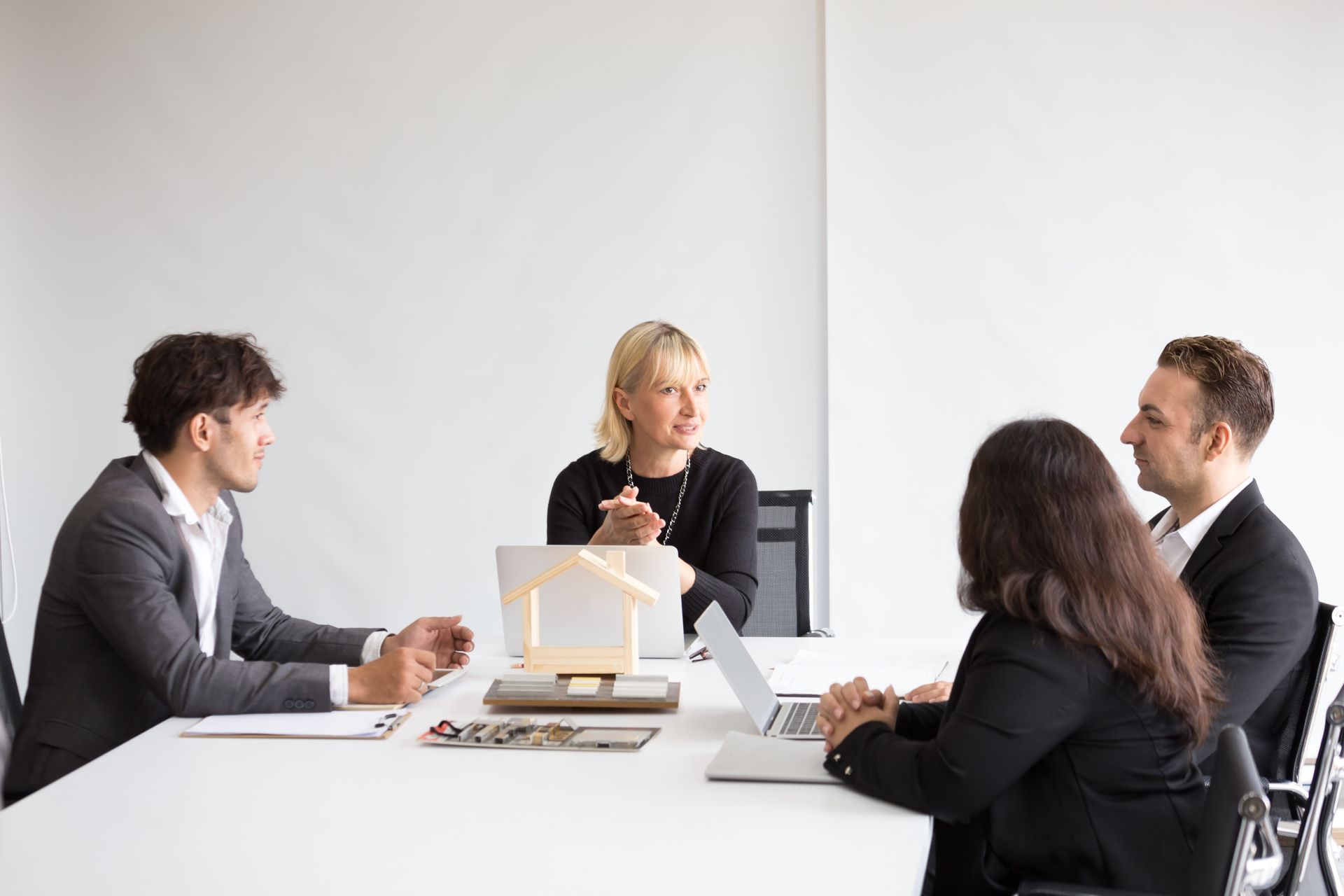 A group of people are sitting around a table with laptops.