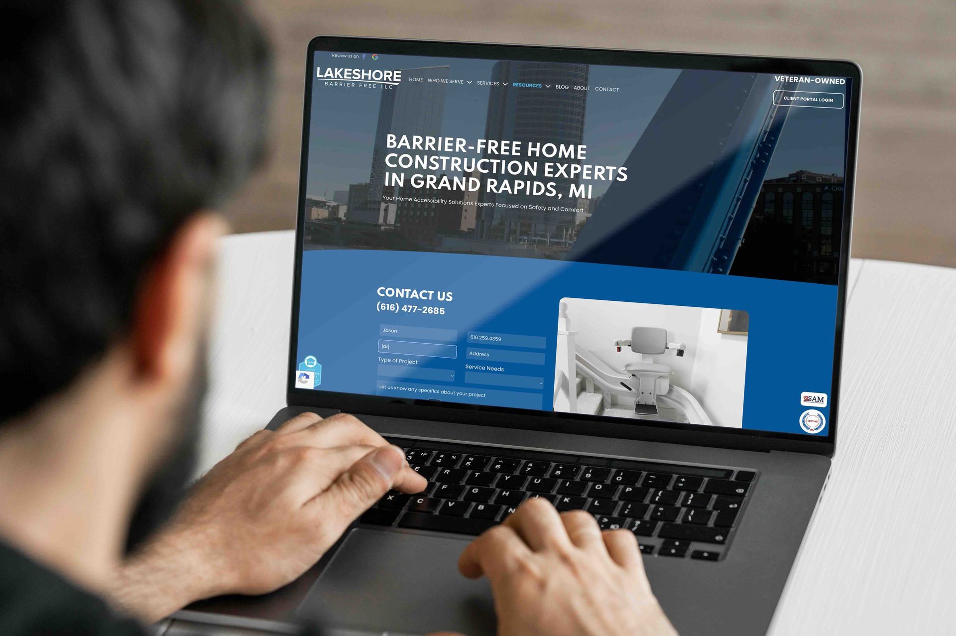 A man is using a lapotop to complete an online form on Lakeshore Barrier Frees website.