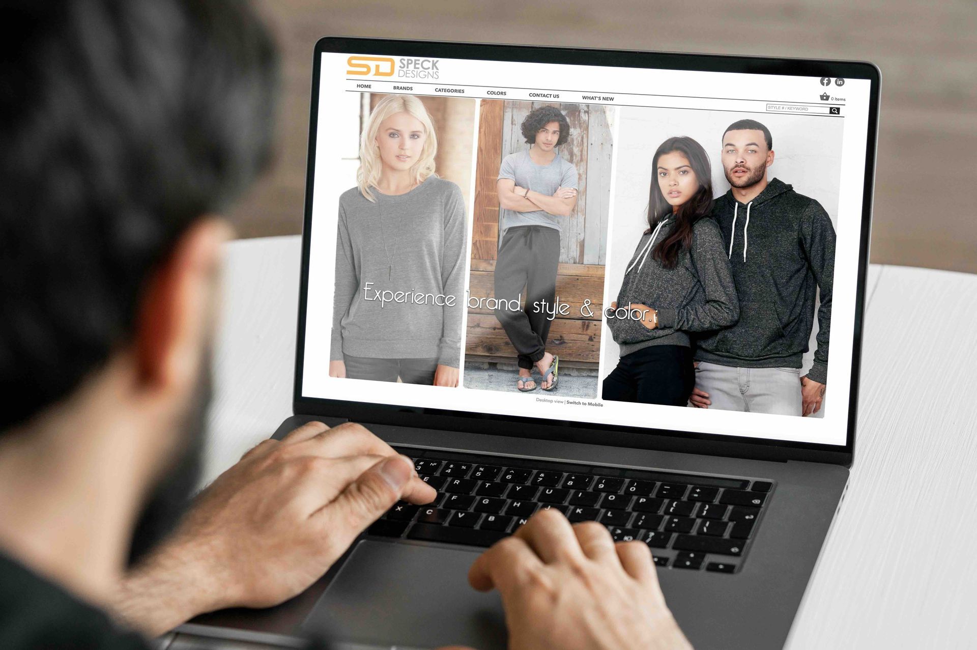 A man is typing on a laptop computer while looking at a website.