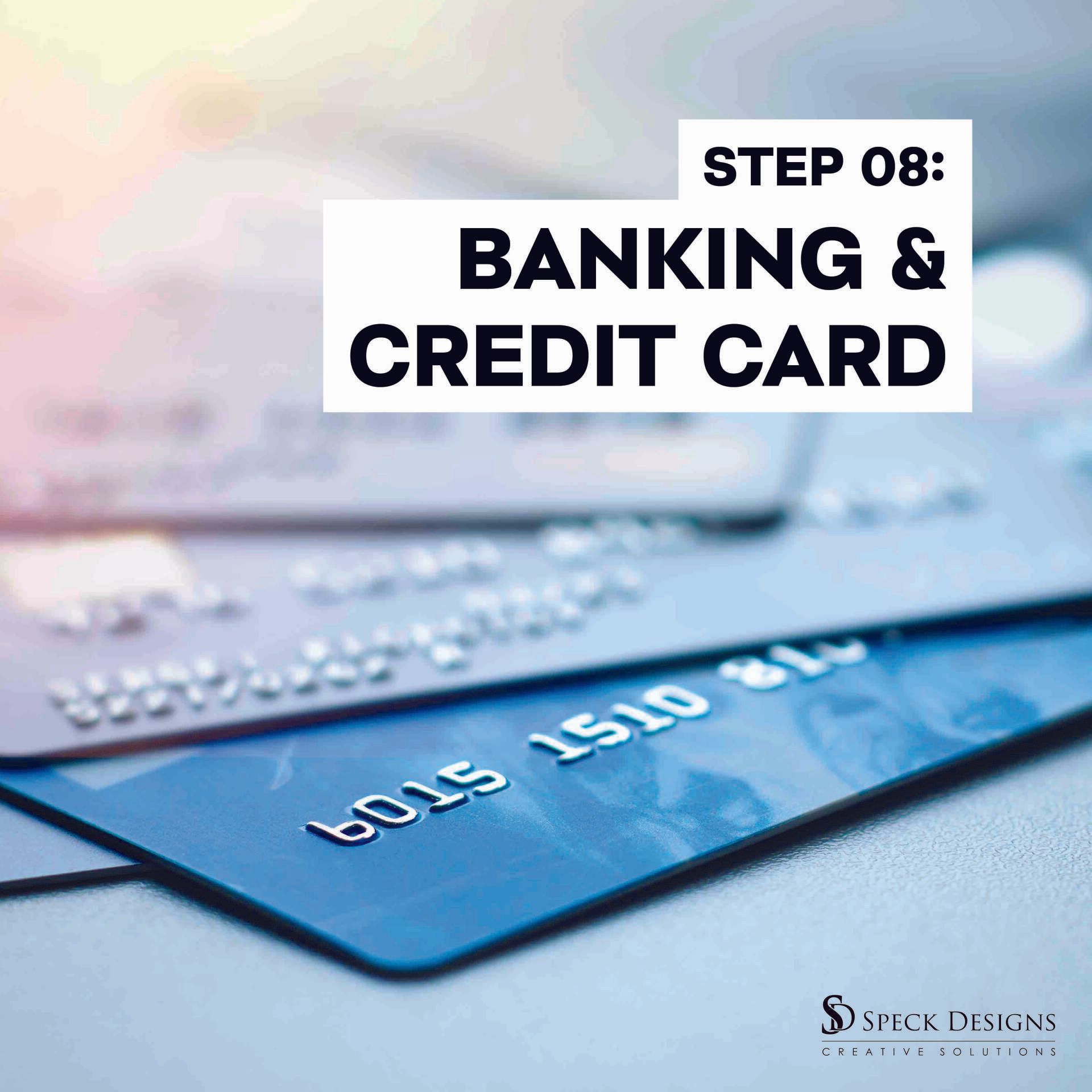 A stack of credit cards with a laptop in the background