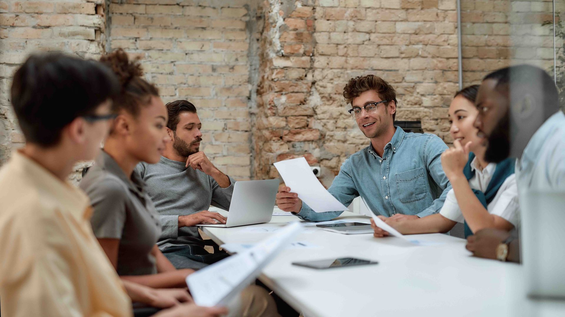 A group of people are sitting around a table having a meeting.