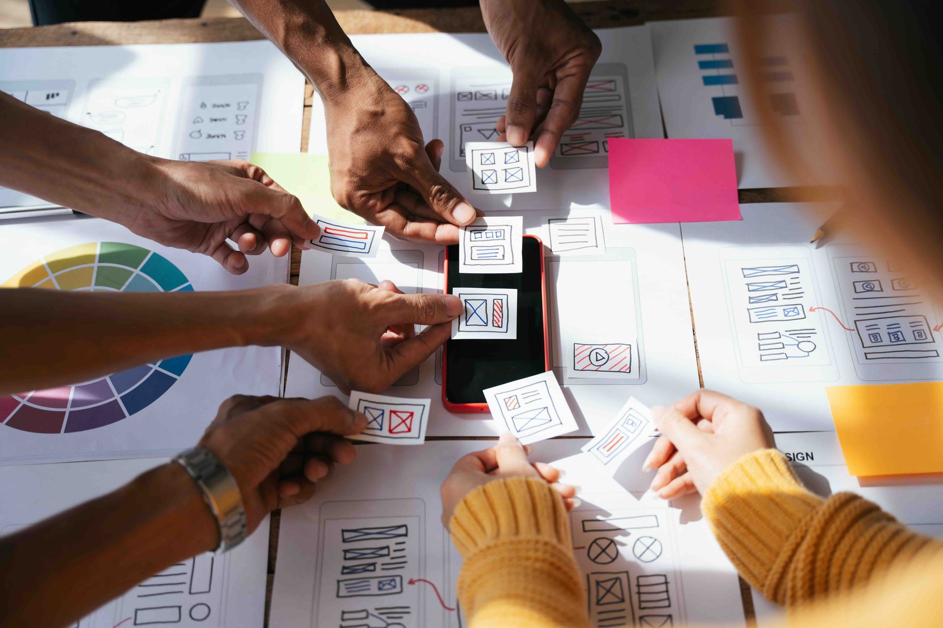 A group of people are sitting around a table working on a wireframe for a website design project.