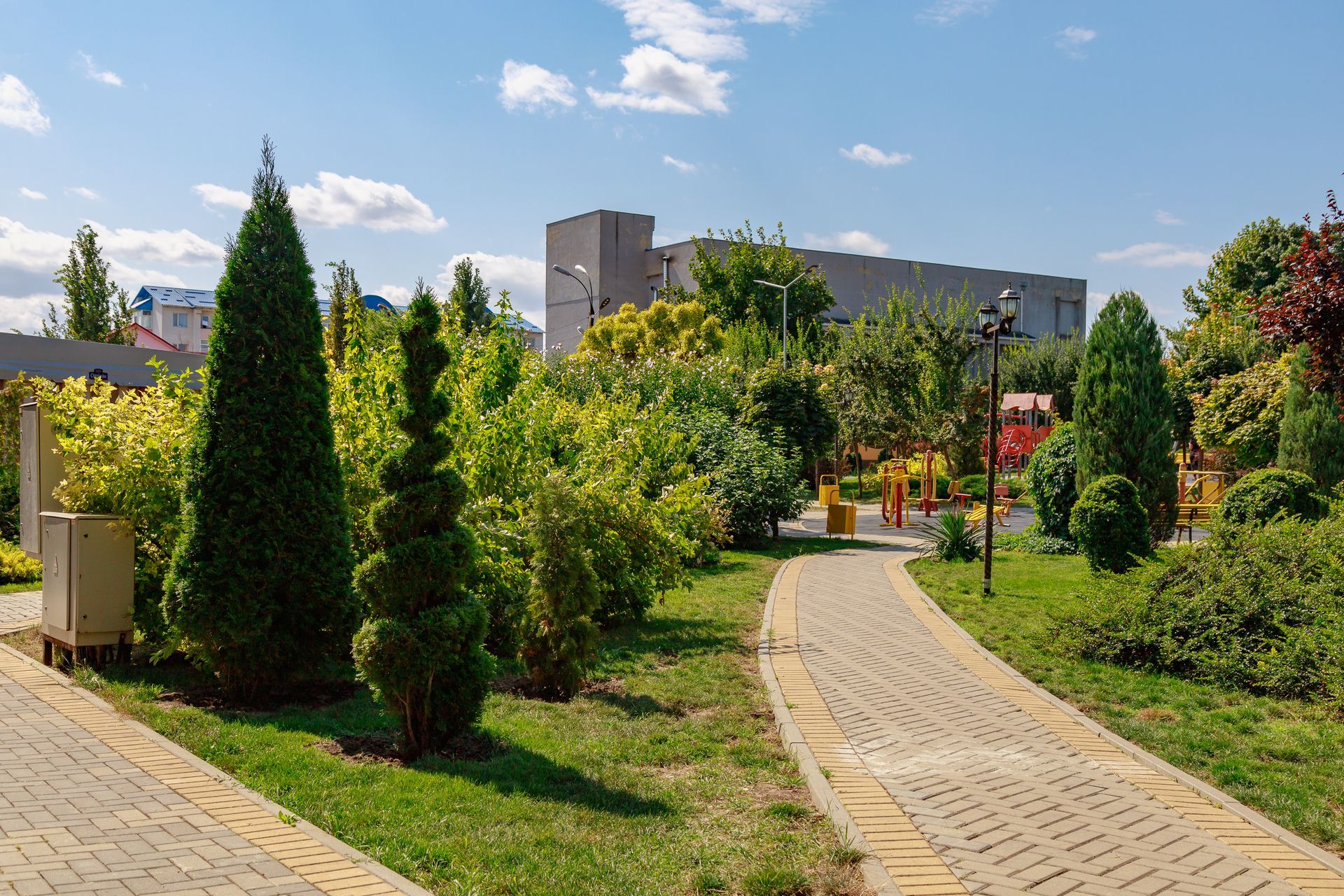 A brick walkway in a park surrounded by trees and bushes.