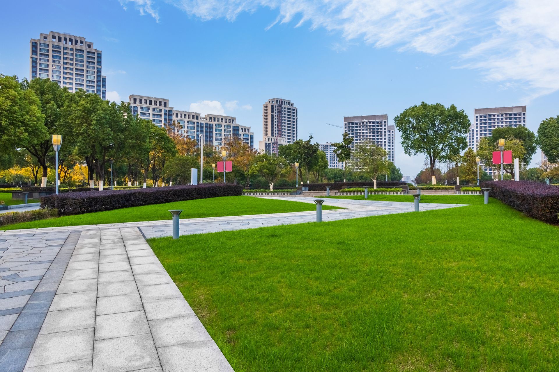 A park with lots of grass and buildings in the background