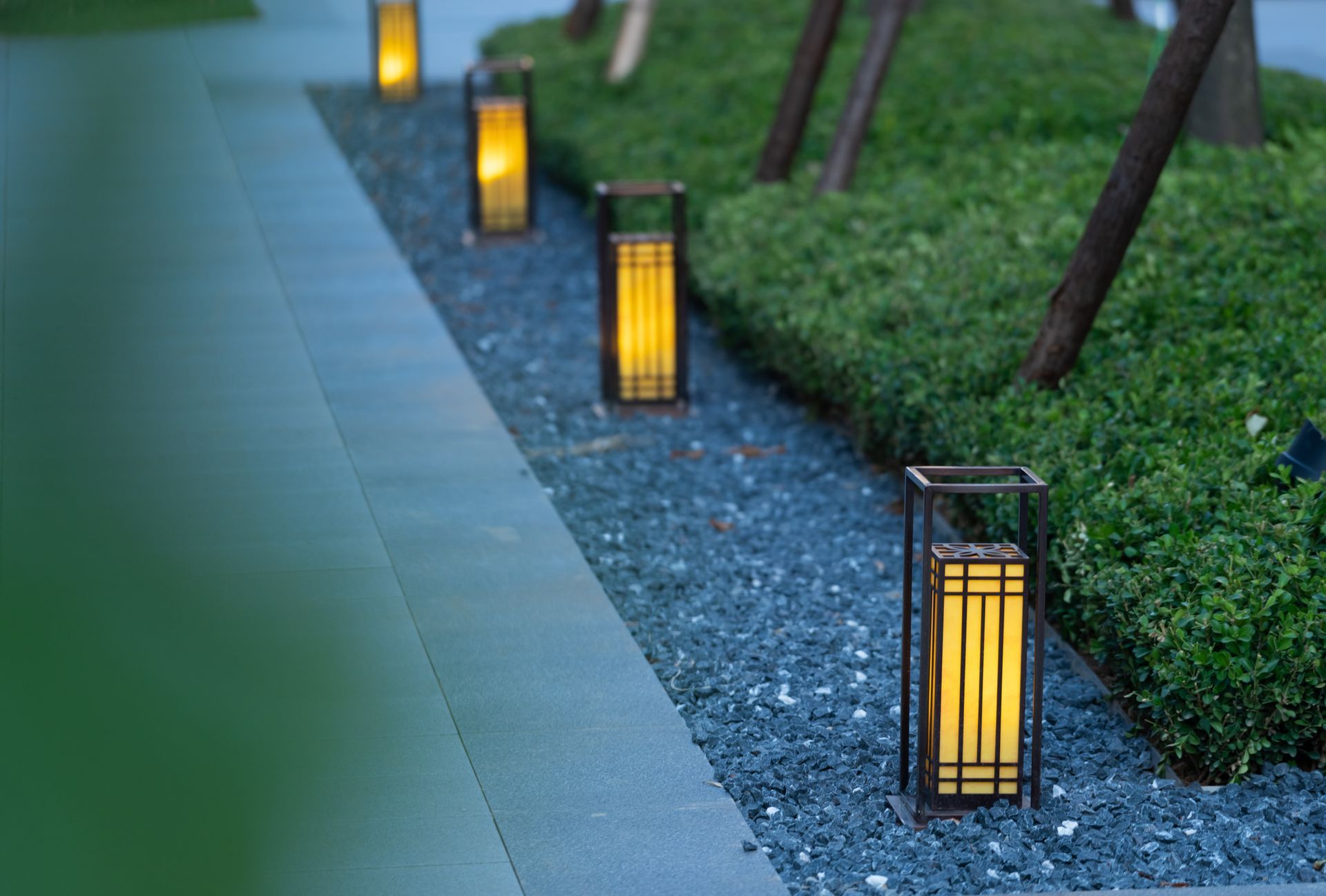 A row of lanterns sitting on top of a gravel path.