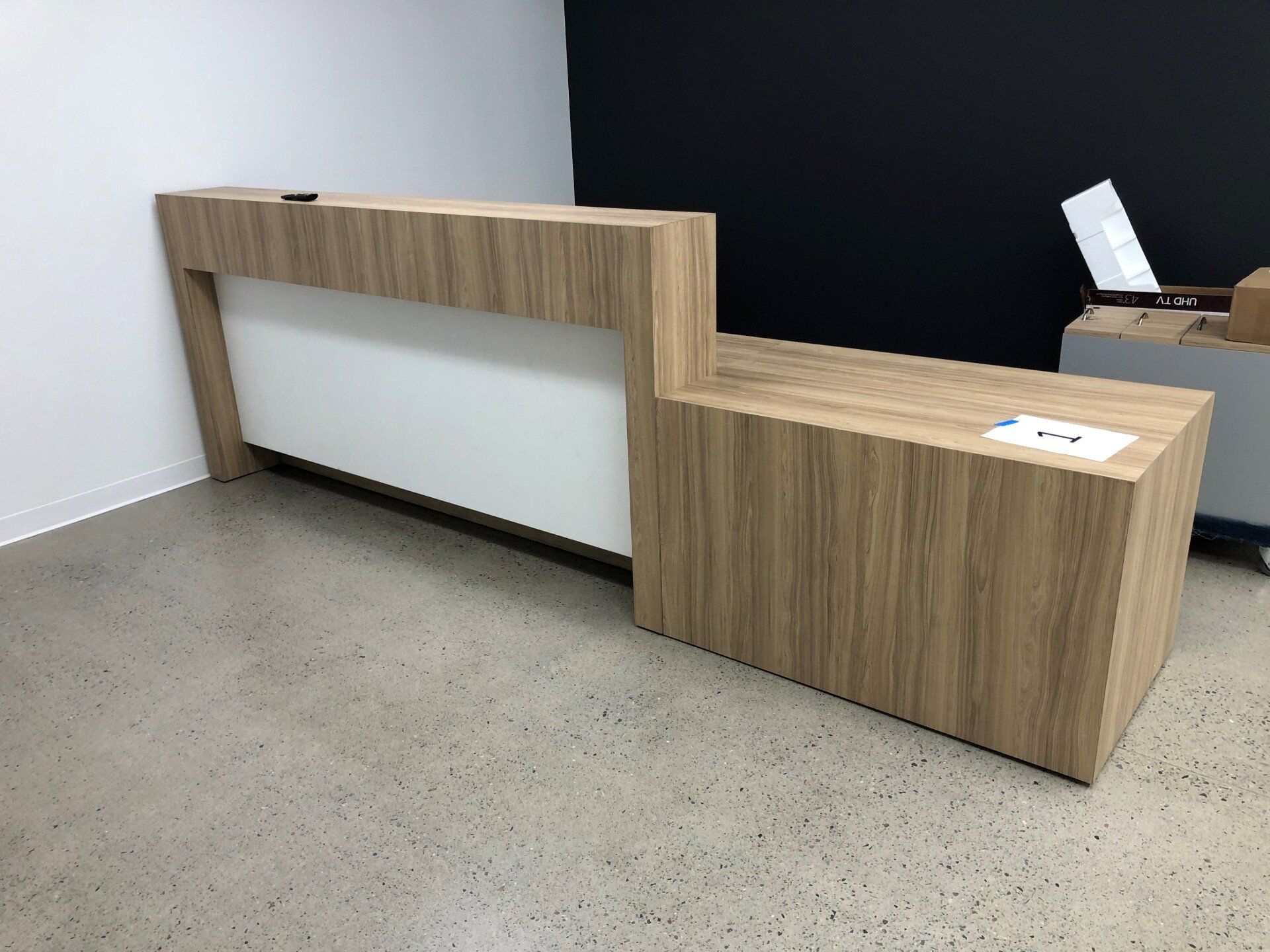 Reception desk with wood grain finish, white panel front, in a modern office.